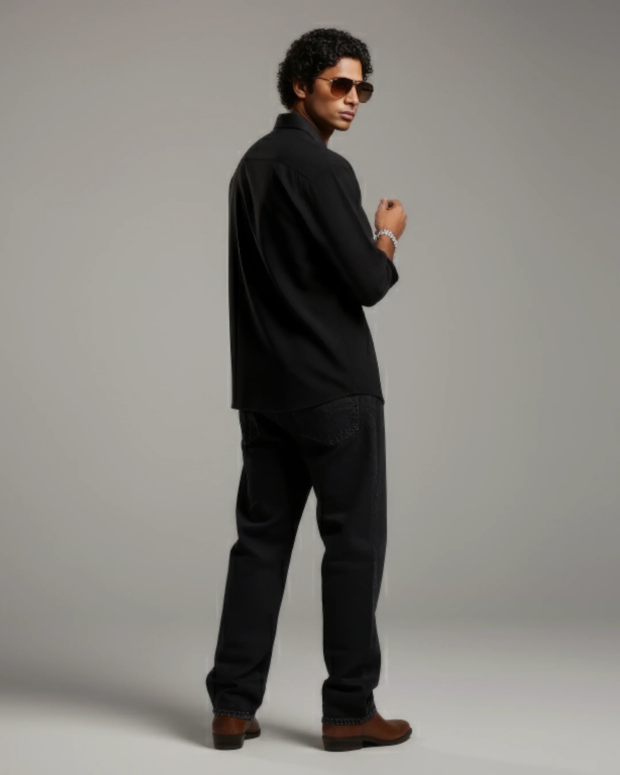 Man in black shirt, jeans, and sunglasses posing confidently, teeside fashion.