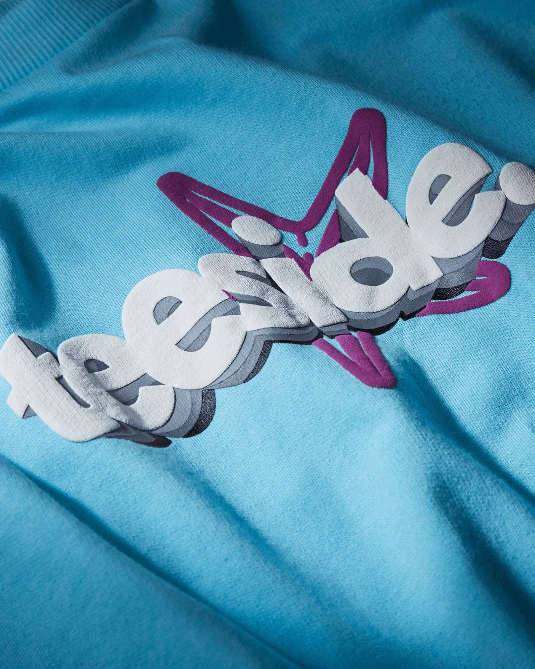 teeside graphic logo on blue t-shirt with 3D white letters and purple star outline