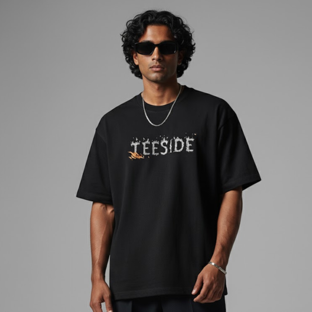 Man wearing black oversized t-shirt with teeside graphic, sunglasses, and silver chain