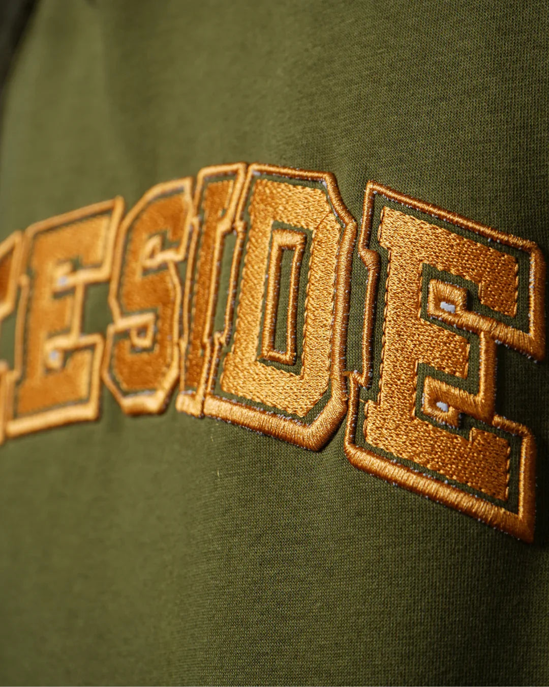 teeside gold embroidered text on olive green fabric closeup