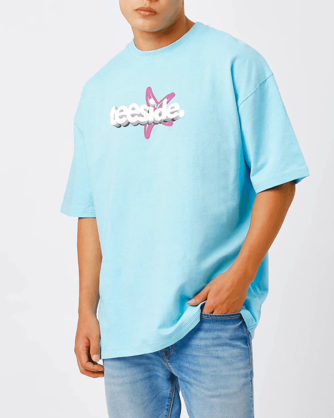 Man wearing light blue teeside t-shirt with bold logo and pink star graphic, casual style