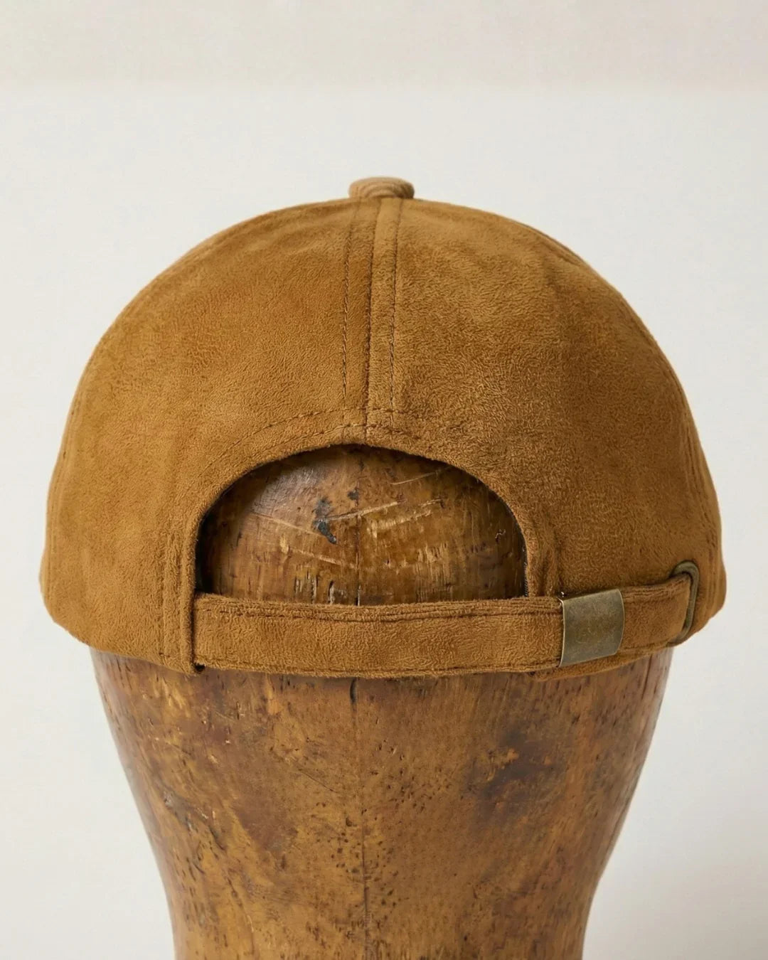 Back view of brown suede baseball cap with metal strap, teeside accessory