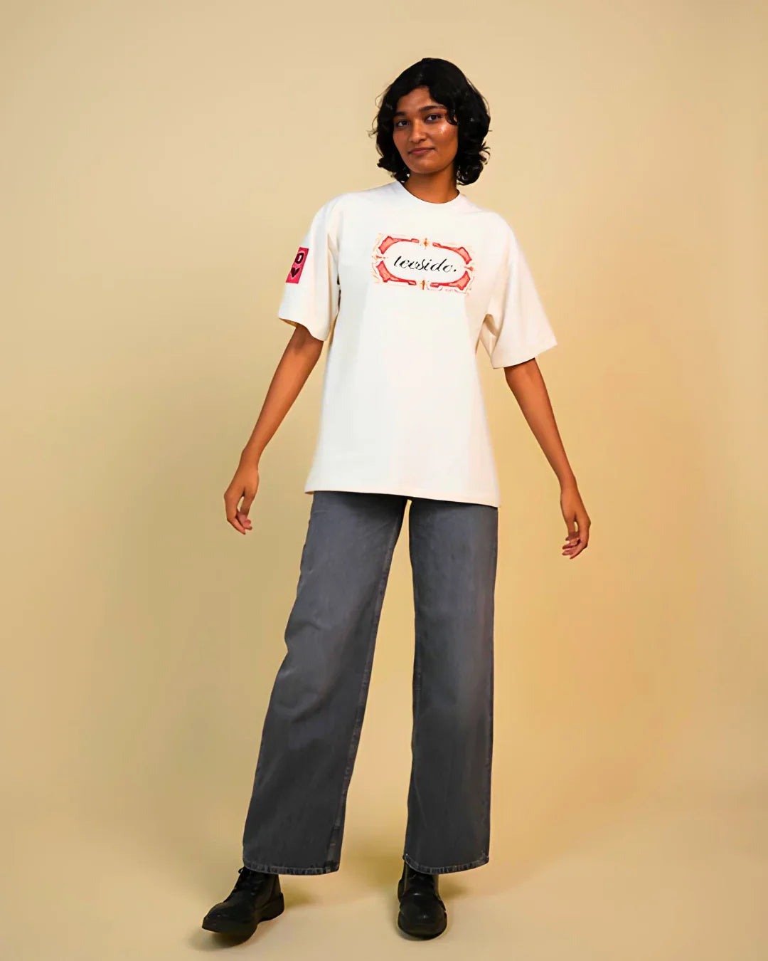 Model wearing teeside graphic white t-shirt, gray wide-leg jeans, and black shoes