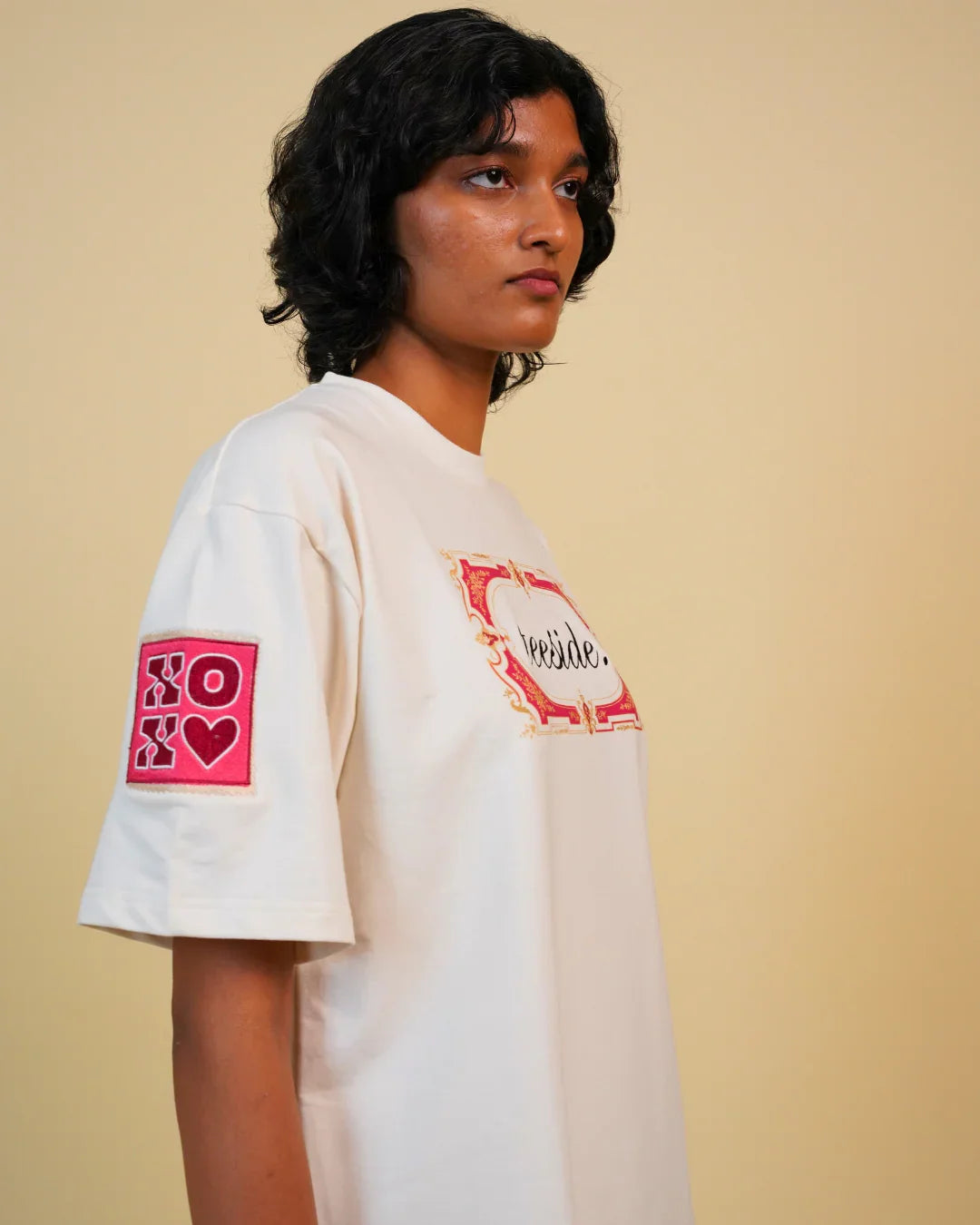 White teeside t-shirt with ornate front logo and pink XOXO patch on sleeve