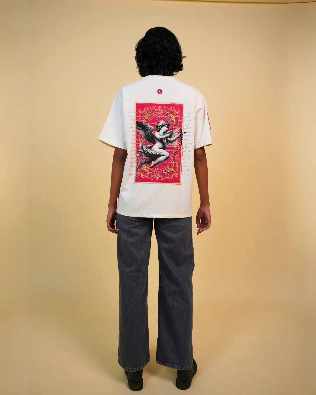 Person wearing teeside graphic t-shirt with angel and red ornate design on the back