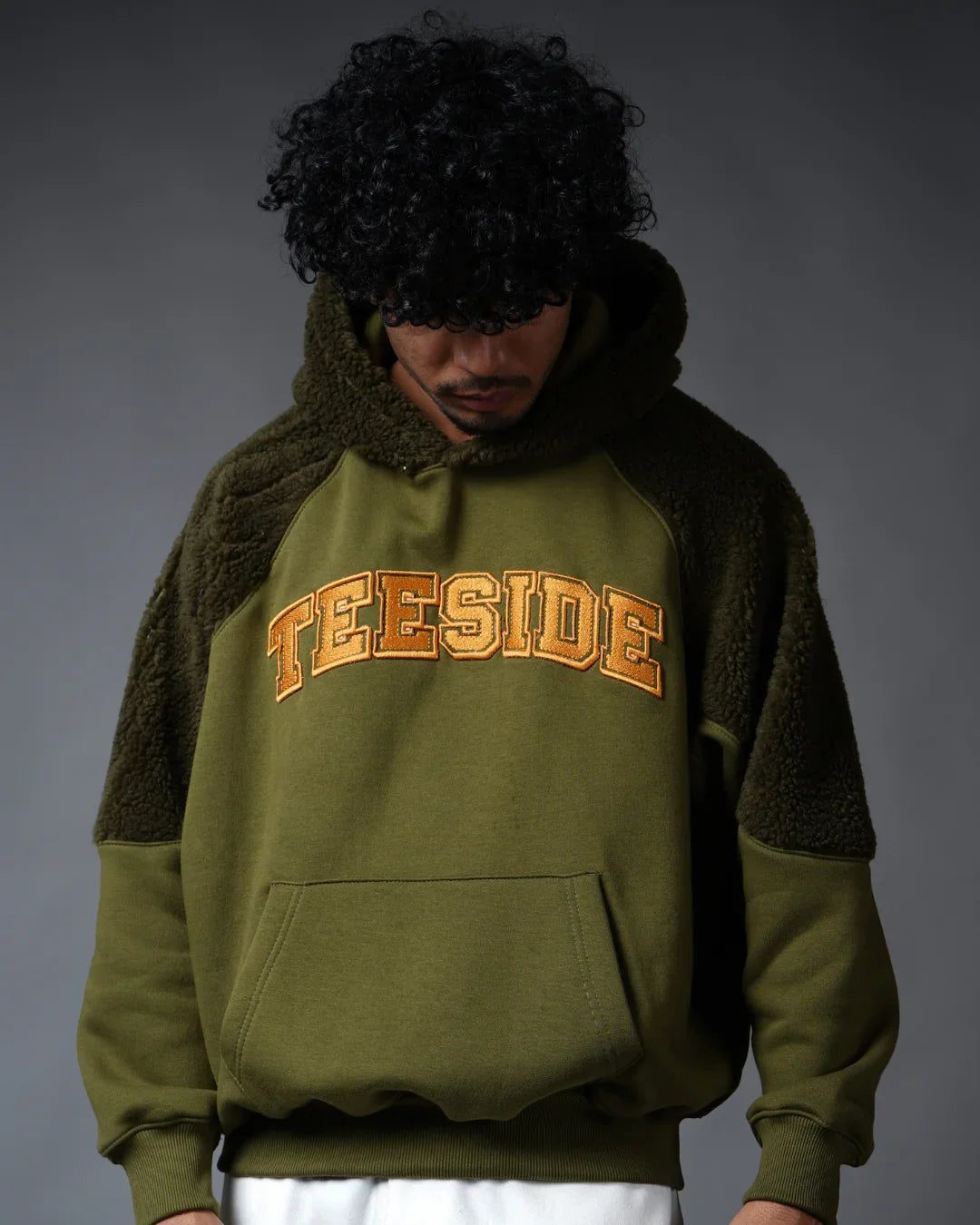Man wearing green hoodie with sherpa panels and TEESIDE text on chest