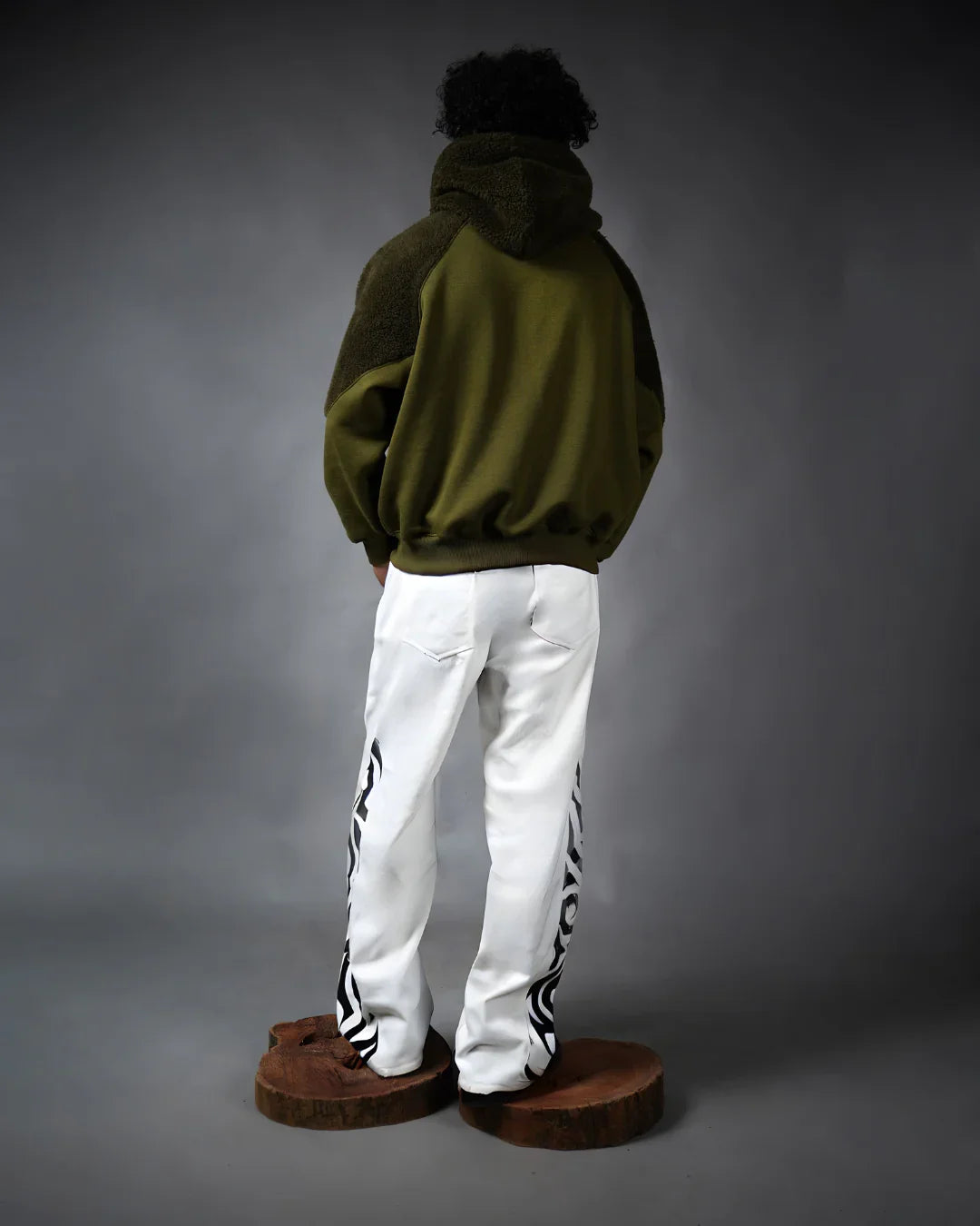teeside model in green hoodie and white pants with black side designs, studio background