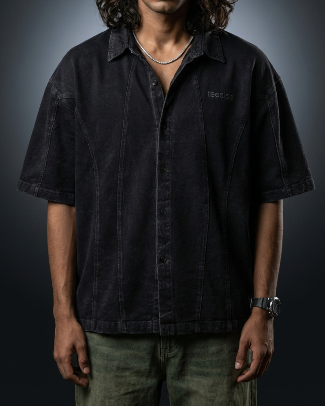 Model wearing dark short sleeve button-up shirt with teeside logo