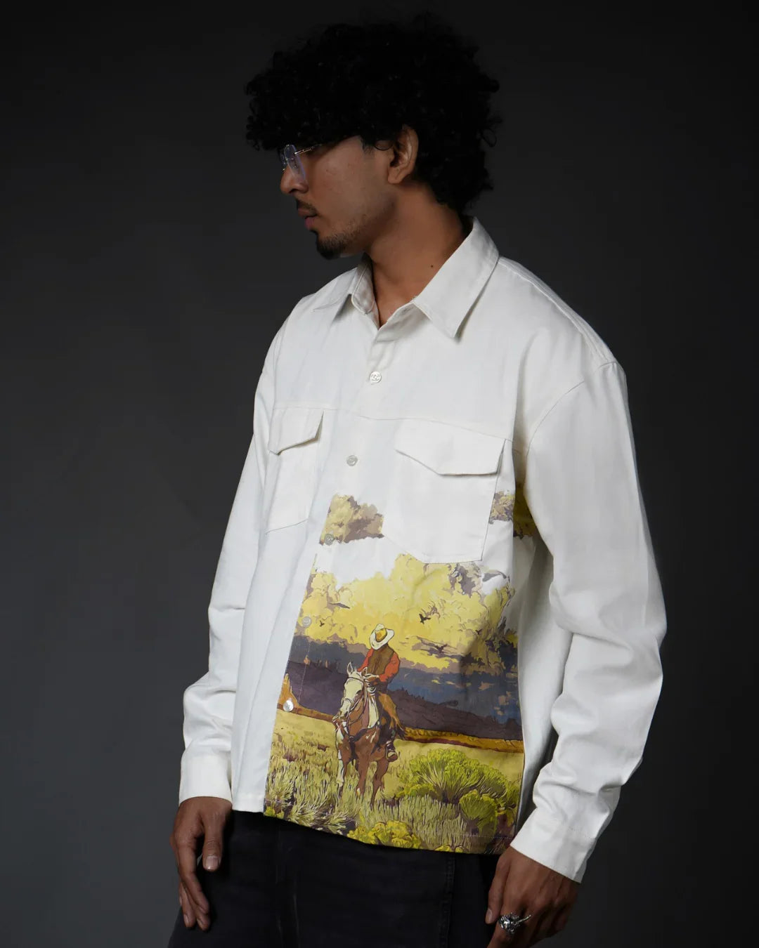 Man wearing teeside white shirt with cowboy landscape print on front, side view