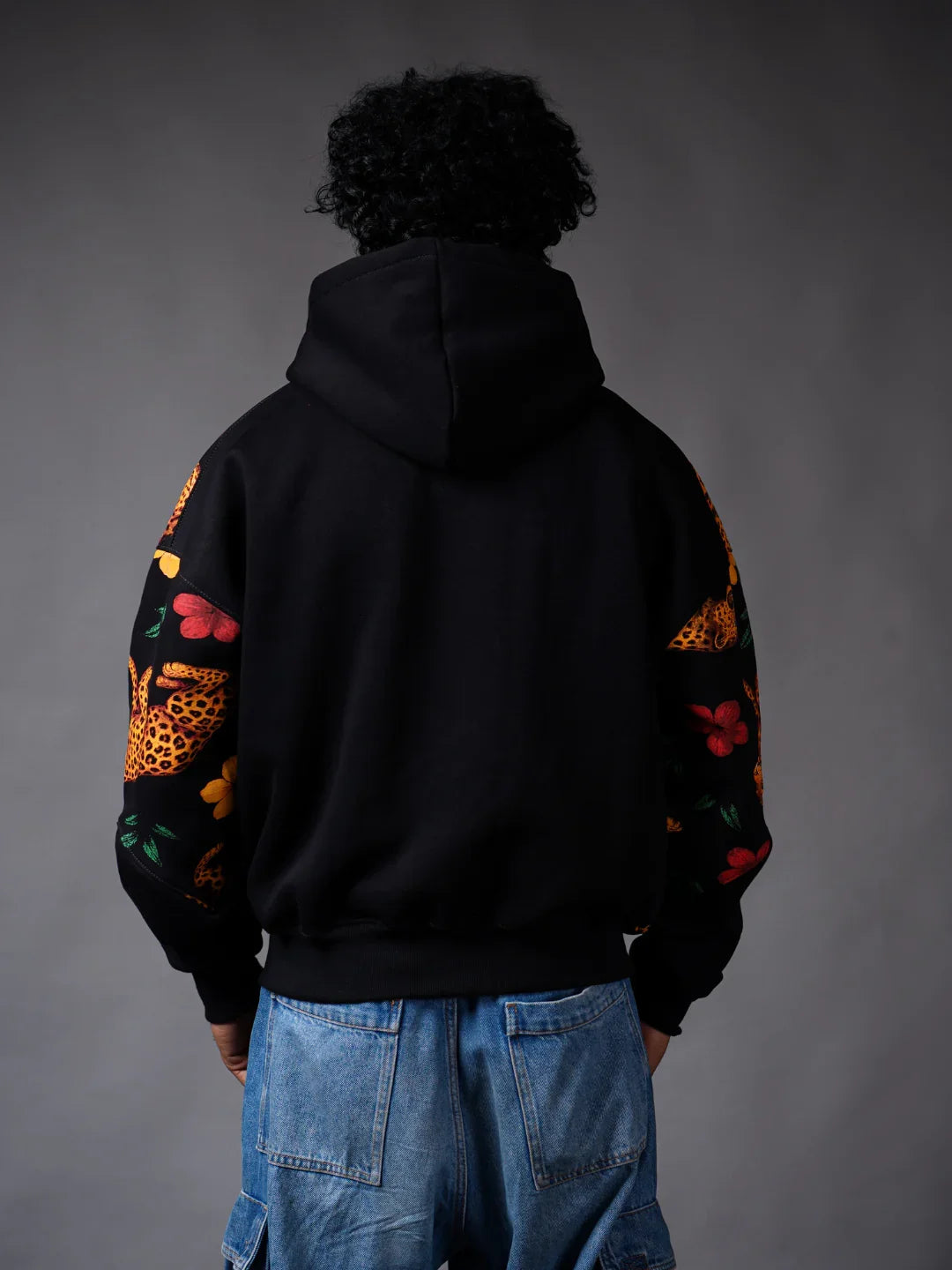 Back view of person wearing a teeside black hoodie with floral and leopard sleeve designs